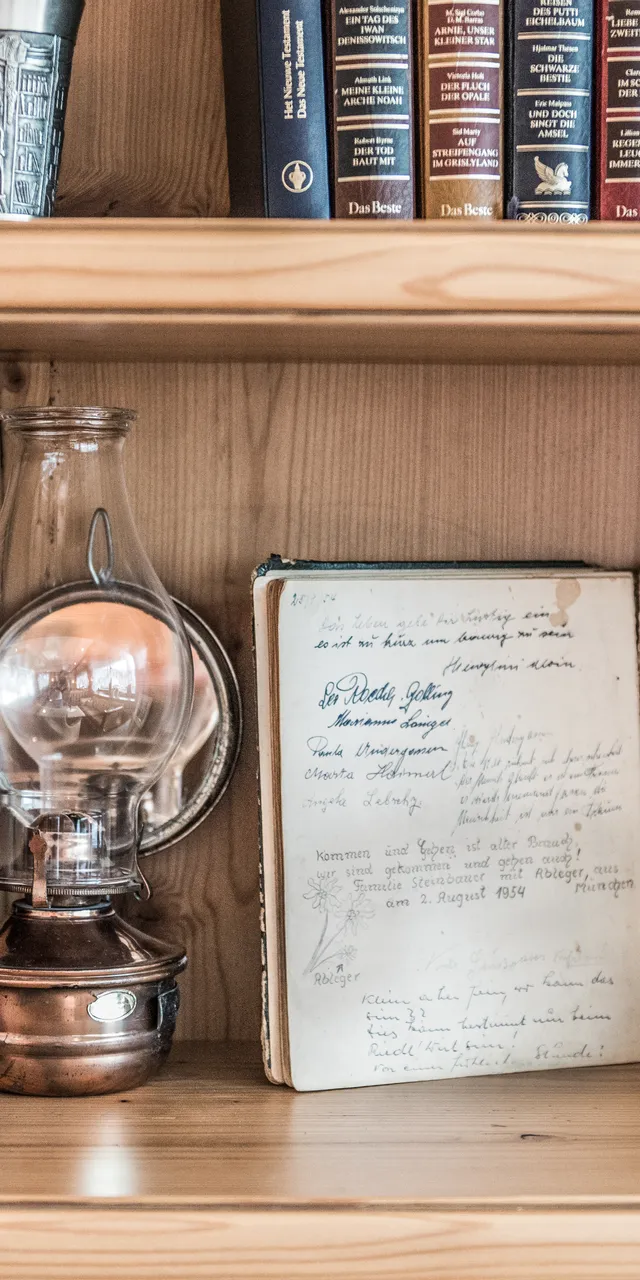 Bookshelf with vintage oil lamp, guest book, old photos, and antique handwritten journal