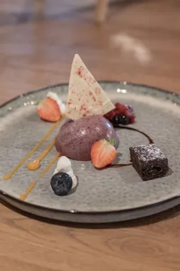 Gourmet berry mousse dessert with white chocolate shard, fruit, brownie and caramel drizzle