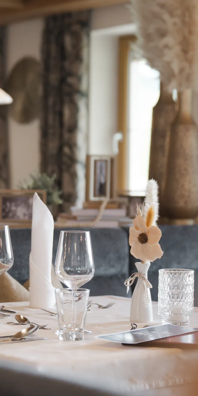 Elegant dining table with glasses, napkins, and a floral centerpiece