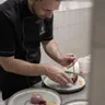 Koch richtet ein Gourmet-Dessert mit Beerengarnitur in Profiküche an