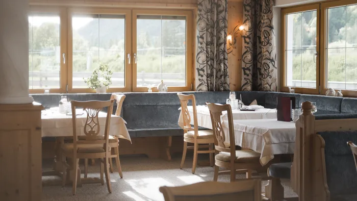 Cozy restaurant interior with wooden chairs, tables, and large windows