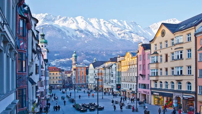 Bunte Gebäude in der Altstadt von Innsbruck mit schneebedeckten Alpen im Hintergrund