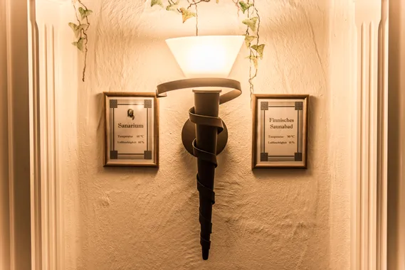 Wandlampe zwischen Schildern für Sanarium und Finnisches Saunabad mit Temperatur- und Feuchtigkeitsangaben