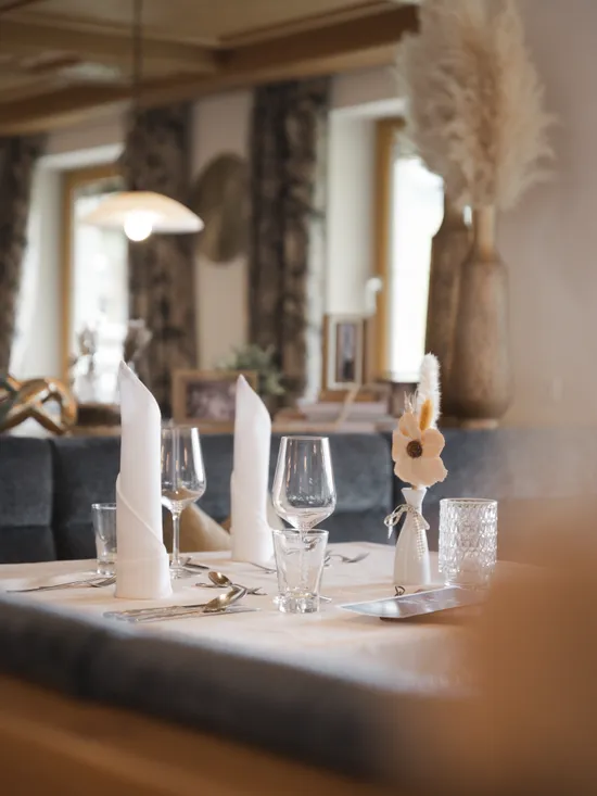 Eleganter Esstisch mit weißen Servietten, Weingläsern und Blumengesteck