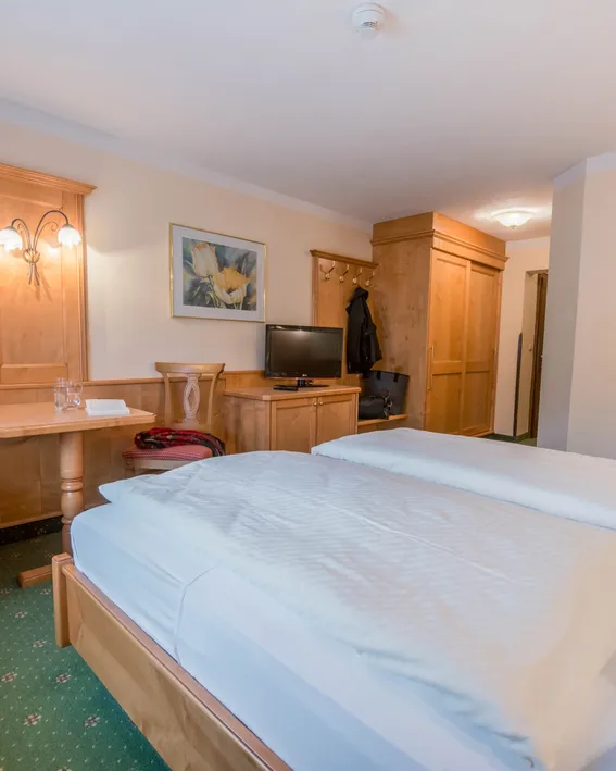 Cozy hotel room with double bed, wooden furniture, TV, and corner seating area