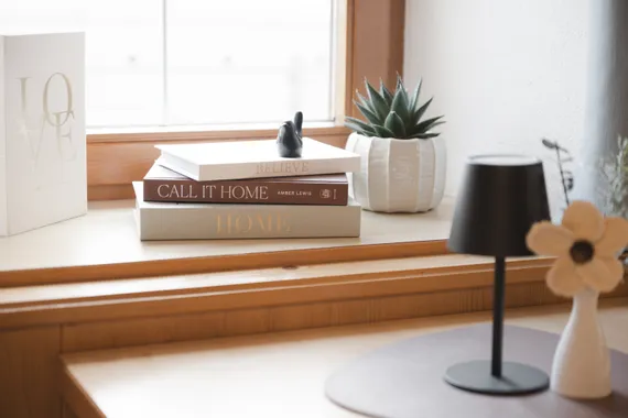 Decorative books stacked on a windowsill with a potted succulent nearby