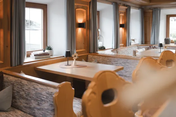 Gemütliche Essecke mit Holzbänken, Tisch und Deko nahe einem Fenster mit Vorhängen