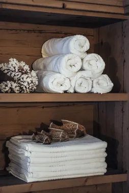 Weiße Spa-Handtücher auf Holzregalen mit Korallendeko und Fischfiguren aus Holz