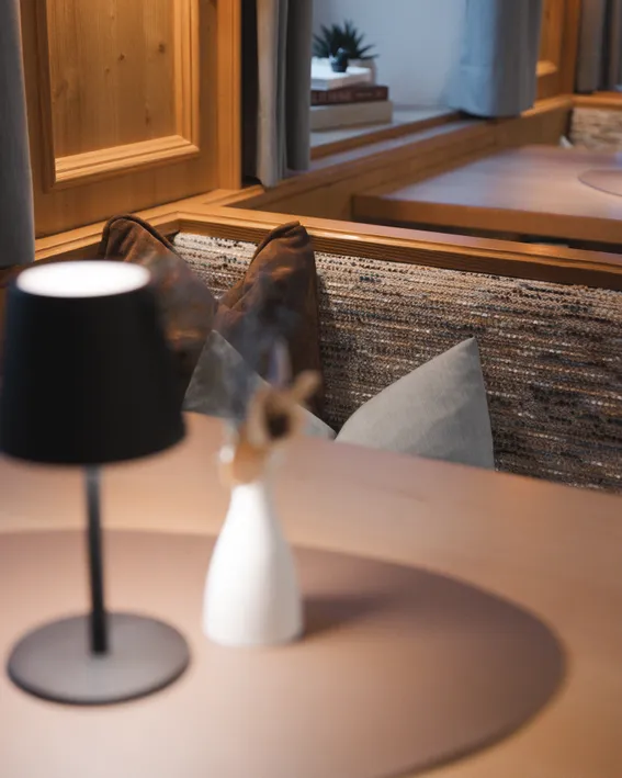Gemütliche Sitzecke mit Kissen und moderner Lampe auf Holztisch