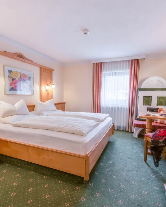 Gemütliches Hotelzimmer mit Doppelbett, Fernseher, Sitzecke und grünem Teppich