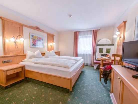Gemütliches Hotelzimmer mit Doppelbett, Fernseher, Sitzecke und grünem Teppich
