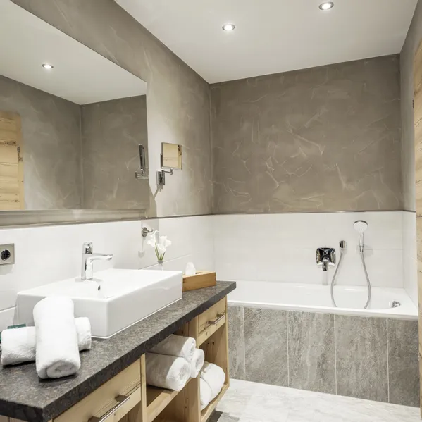 Modernes Badezimmer mit Badewanne, Aufsatzwaschbecken, Holzmöbeln und stimmungsvoller Beleuchtung