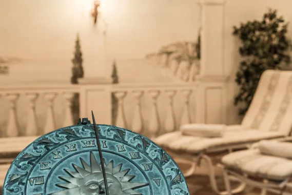 Dekorative Sonnenuhr in einem Spa-Ruheraum mit Liegestühlen und Wandmalerei