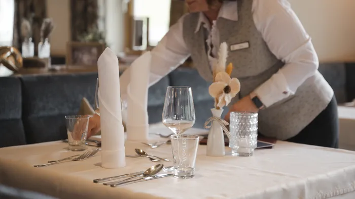 Kellnerin deckt Tisch mit gefalteten Servietten im eleganten Restaurant