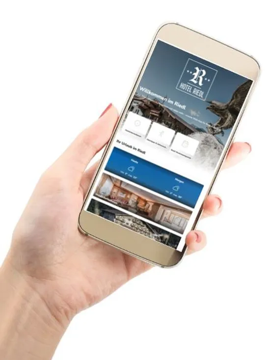 Hand hält Smartphone mit der Startseite der Hotel Riedl Website
