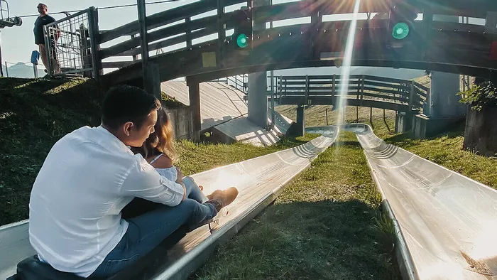 Paar sitzt auf Sommerrodelbahn in einem Bergfreizeitpark