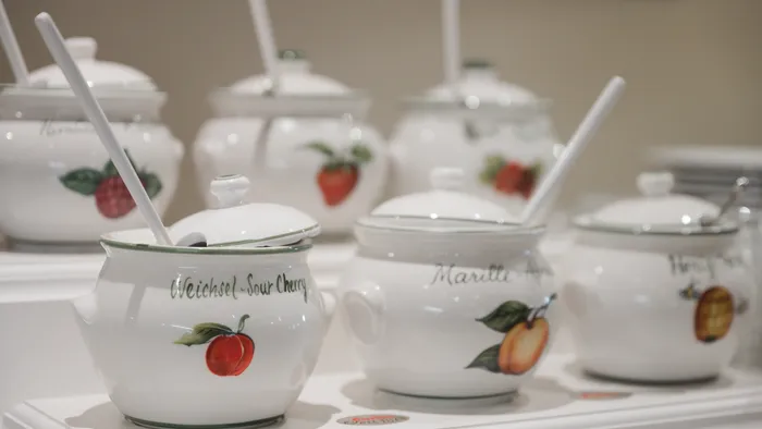 Ceramic jars with fruit illustrations and ladles on display