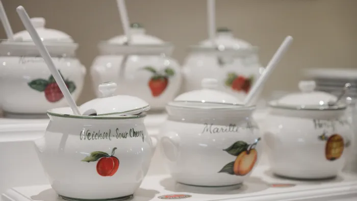 Keramiktöpfe mit Früchteillustrationen und Kellen im Display