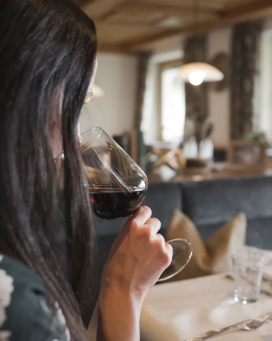 Frau nippt an Rotwein an einem Restauranttisch mit weißen Servietten