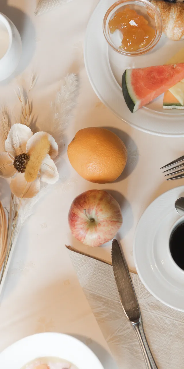 Breakfast table with breadbasket, coffee, fruit, and a news leaflet