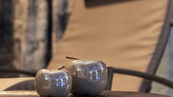 Two ceramic apple decorations on a table in front of a beige spa lounge chair