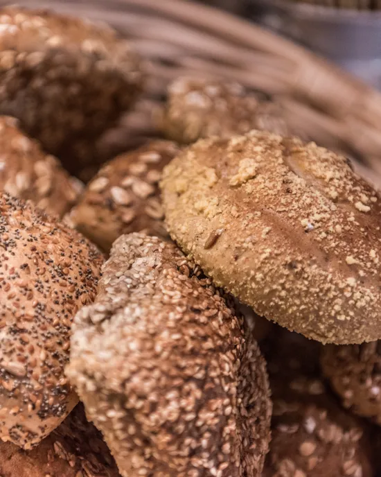 Assortment of whole grain bread rolls with seeds in a wicker basket