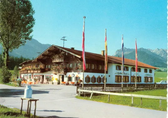 Traditionelles Alpen-Gasthaus mit Außensitzplätzen, Fahnen und Bergkulisse