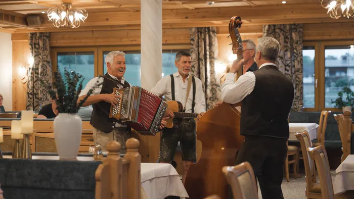 Traditional folk band playing accordion, guitar, and upright bass in a cozy wooden venue