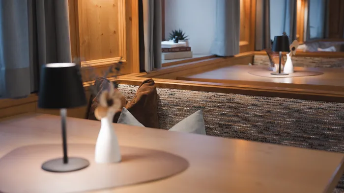 Modern cozy dining area with wooden decor, black lamp, and decorative vase