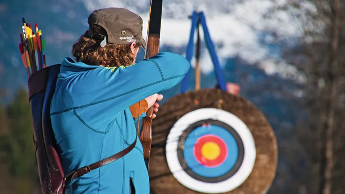 Archer aiming at a colorful archery target outdoors in a mountain setting