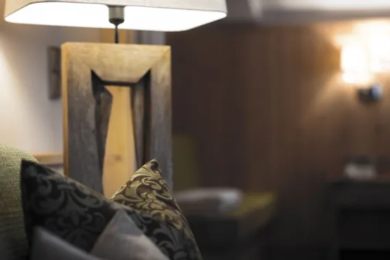 Gemütliches Hotelzimmer mit Zierkissen, Holzlampe und warmer Ambientebeleuchtung