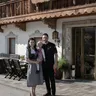 Familie in Tracht vor einem Alpen-Gasthaus mit Holzbalkon und Blumenschmuck