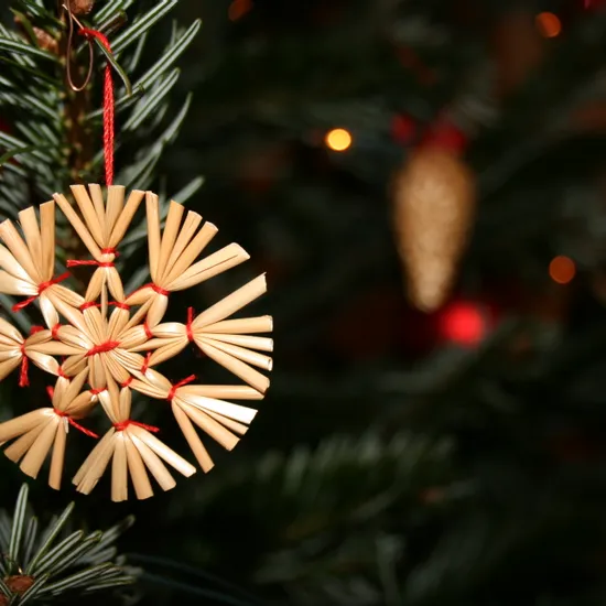 Traditional straw star ornament hanging on a Christmas tree branch