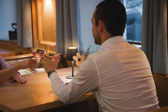 Paar stößt mit Weingläsern an einem gemütlichen Restauranttisch an