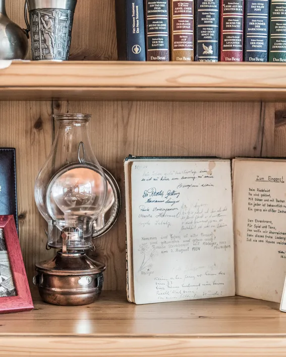 Bücherregal mit antiker Öllampe, Gästebuch, alten Fotos und handgeschriebenem Tagebuch