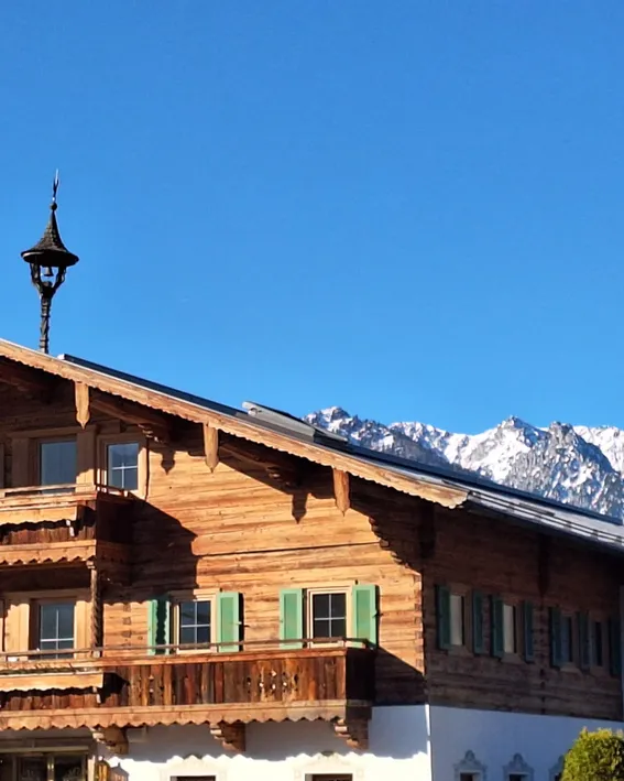Holzchalet in den Alpen mit Bergen im Hintergrund unter klarem Himmel
