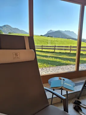 Hotel lounge chair by a window with mountain and meadow view