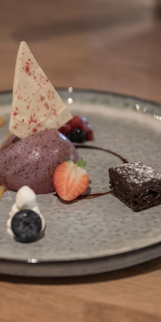 Gourmet-Dessert mit Beerenmousse, Brownie, Erdbeeren, Heidelbeere und weißer Schokoladensplitter