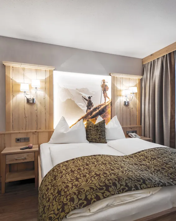 Gemütliches Alpenhotelzimmer mit Doppelbett, Bergkunst und Holzmöbeln