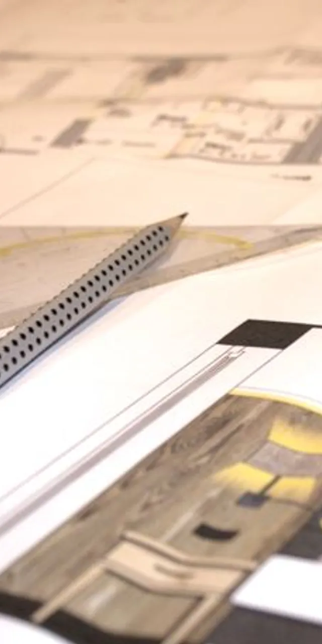 Architectural floor plans with scale ruler, triangle, and pen on drafting table