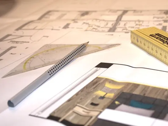 Architektonische Grundrisse mit Maßstab, Geodreieck und Stift auf dem Zeichentisch