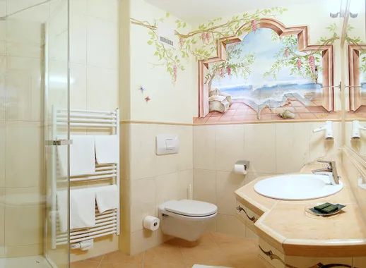 Helles Hotelbad mit Wandbild, Glasdusche, Handtuchwärmer und wandhängender Toilette