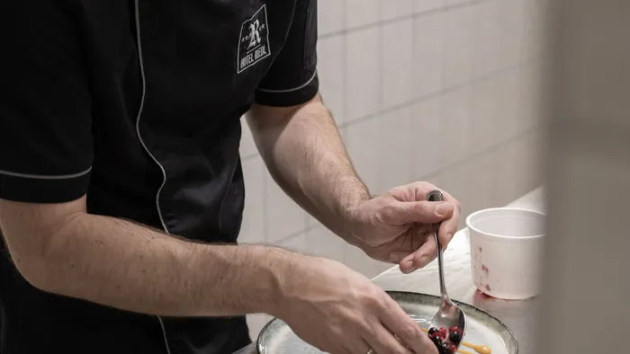 Koch richtet ein Gourmet-Dessert mit Beerengarnitur in Profiküche an