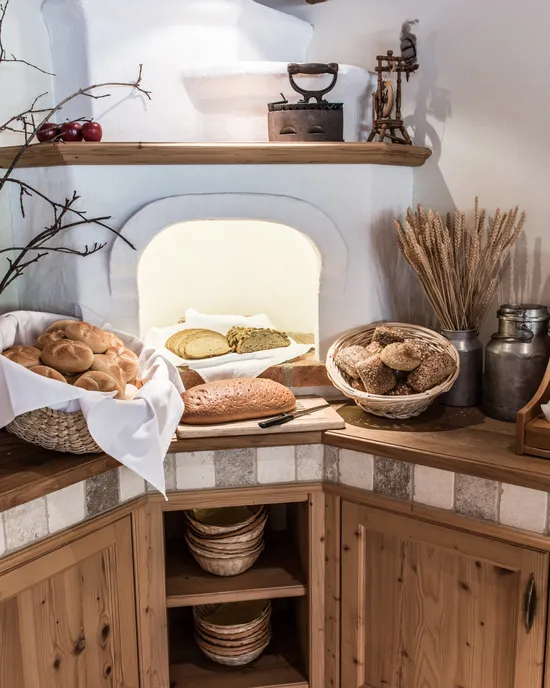 Rustic breakfast buffet with fresh bread rolls, cereals, and labeled jam jars