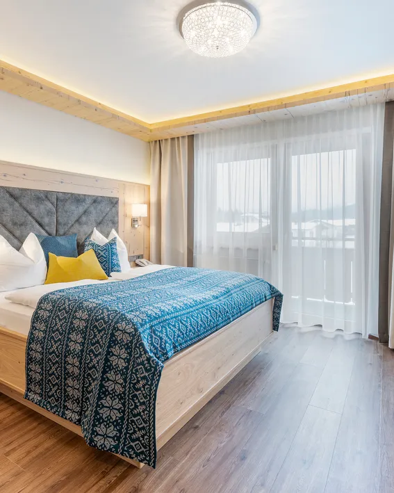Modernes Hotelzimmer mit Holzmöbeln, Doppelbett, blauer Dekoration und Flachbildfernseher