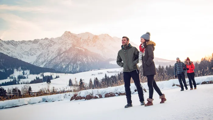 Group of people winter hiking through snowy alpine landscape at sunset