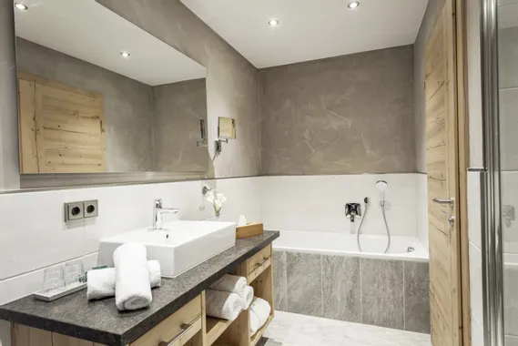 Modernes Badezimmer mit Badewanne, Aufsatzwaschbecken, Holzmöbeln und stimmungsvoller Beleuchtung